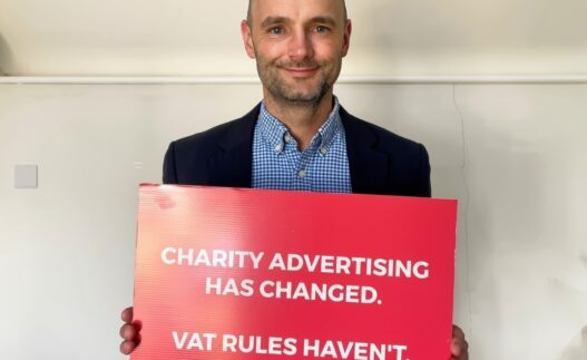 Image of Luke Hall holding red card with wording vat on social media advertising